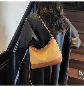 Detail of vintage suede half-moon bag with leather trim and gold chain strap