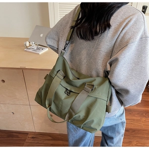 Detail of army green nylon messenger bag with adjustable strap and black metal hardware