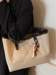 Minimalist beige canvas tote bag with brown PU leather trim and colorful beaded pendant