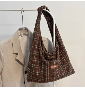 Detailed close-up of brown checkered hobo tote bag with a leather logo on grey blazer
