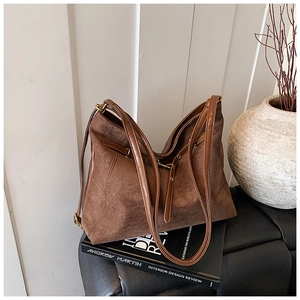 Detail of dark brown matte suede tote bag placed on vintage books for daily commute