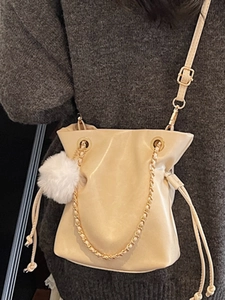 Fashionable beige drawstring bucket bag with gold chain and white fur ball charm for women
