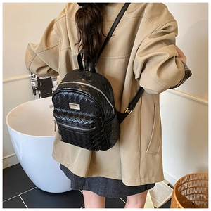 Détail d'un sac à dos tissé noir avec fermeture éclair argentée et plaque en métal chic