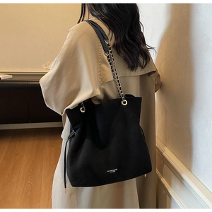 Détail du sac seau noir en nylon avec bandoulière en cuir et chaîne et pompons