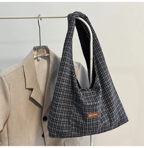Close-up of checkered canvas tote bag with brown leather label and plaid texture details