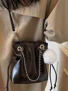 Fashionable dark brown leather drawstring bucket bag with plush charm and chain strap