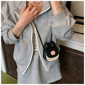 Détail d'un mini sac bandoulière noir avec un motif pomme rouge et un nœud noir décoratif