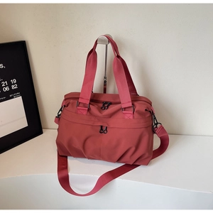 Close-up of brick red travel tote bag with durable nylon handles and side zippers