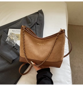 Detail of vintage brown suede shoulder bag with gold chain strap in a lifestyle setting