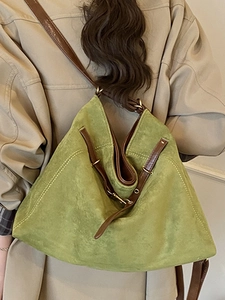 Retro large capacity green suede tote bag with brown straps worn over a beige trench coat
