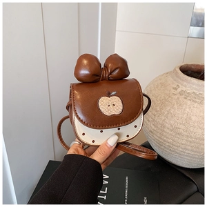 Détail du mini sac pomme avec nœud en cuir et motif à pois sur le bas du sac