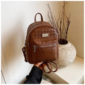 Vue détaillée du sac à dos marron en similicuir tressé avec étiquette métallique
