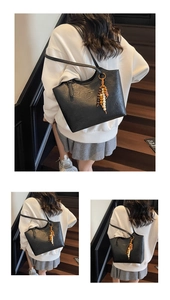 Close-up of black lychee grain tote bag with gold logo and wooden bead tassel detail