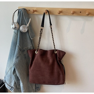Vue détaillée du sac seau en daim marron foncé avec chaîne dorée et cordon de serrage chic