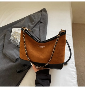 Top-down view of a vintage brown suede bag with black leather panels and a chain strap