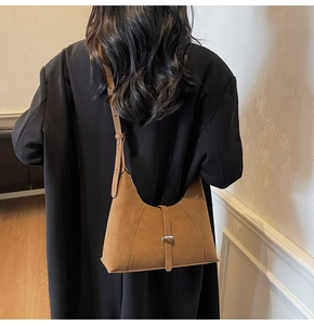 Brown suede crescent shoulder bag with stitching detail shown on a female model