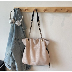 Détail du sac seau à cordon avec ferrures dorées et bandoulière chaîne en daim beige