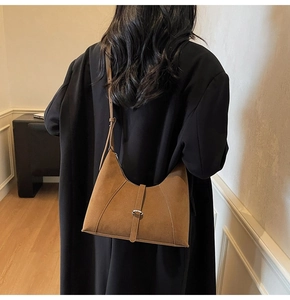 Close-up of brown suede shoulder bag with silver buckle and fine leather texture