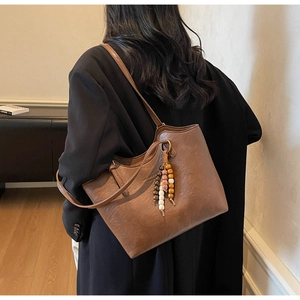 Detail view of large dark brown tote bag with colorful wooden bead tassel charm on strap