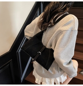 Detail of a black matte leather underarm bag with silver square buckle shown on shoulder
