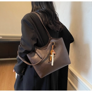 Detail view of brown faux leather tote bag featuring bohemian colorful beaded charm