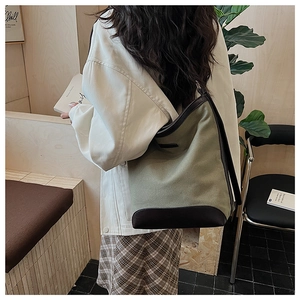 Detailed view of the olive canvas tote bag with brown leather trim in a cozy cafe setting