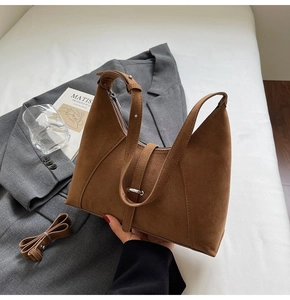 Brown suede crescent shoulder bag with silver buckle detail on a minimalist setup
