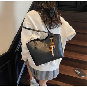 Close-up of black leather tote bag with lychee texture and colorful wooden bead tassel