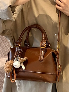 Dark brown oil wax leather pillow bag with white stitching and cute bear charm pendant