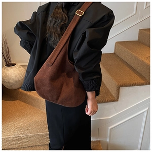 Detail view of large dark brown suede tote bag with retro gold buckle on model