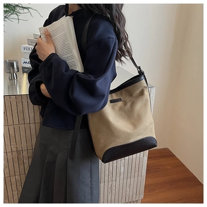 Detail of high-capacity khaki canvas bucket bag with brown leather trim and wide strap