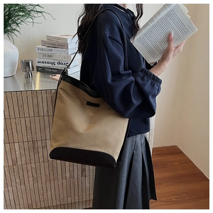 Detail of canvas tote bag with black leather trim and spacious trapezoidal structure