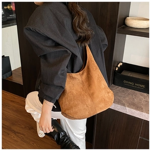 Detailed close-up of a large brown suede shoulder hobo bag in a vintage minimalist style