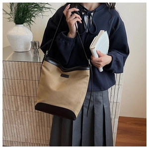Close-up of canvas and brown leather stitching on a minimalist shoulder tote bag