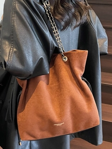 Sac seau en daim marron avec bandoulière chaîne porté par un mannequin stylé