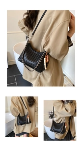 Detail of black woven shoulder bag with silver chain and colorful bead charm accessory