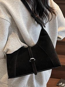 Minimalist black suede crescent shoulder bag with silver buckle worn by a model