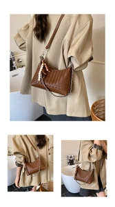Detail of woven crescent crossbody bag with dark brown texture and beaded zipper puller