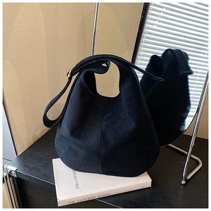 Detail of black matte suede hobo bag with adjustable strap on book with mirror reflection