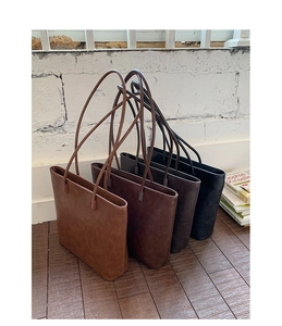 Detailed arrangement of four minimalist tote bags in brown and black on wood floor