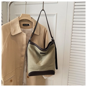Detail of army green canvas hobo bag with leather straps on a khaki trench coat