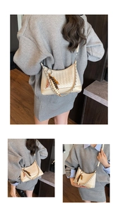 Detail view of beige woven shoulder bag showing fine texture and wooden bead charm