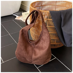 Detailed macro view of dark brown suede hobo bag featuring metal adjustable buckle and soft texture