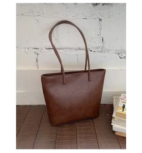Detail of vintage brown tote bag showing textured PU leather finish on a wooden floor