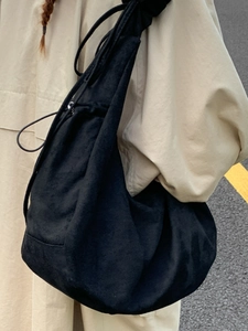 Minimalist black drawstring hobo bag in soft fabric styled on casual shoulder