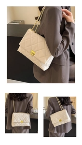 Detailed view of white quilted chain bag with gold metal lock and leather strap