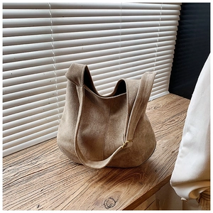 Detail view of khaki faux suede tote bag with metal buckle on a wooden desk