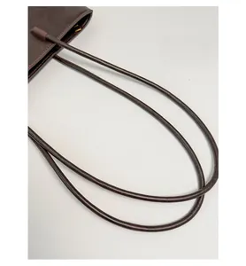Detail shot of the comfortable leather shoulder straps on a minimalist coffee brown tote