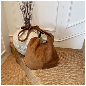 Detailed close-up of dark brown suede hobo tote bag texture with wide strap