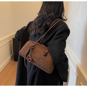 Detail of vintage brown suede shoulder bag with gold logo tag and braided charm